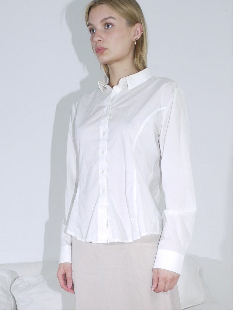 Model wearing a white G-Star button-up shirt with a structured fit and classic collar, paired with a beige skirt. Clean lines and subtle branding give it a sharp, minimal look.