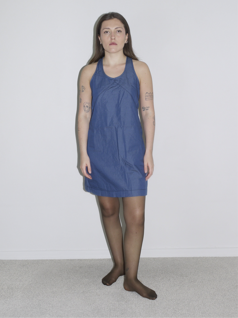 Model in a fitted dark blue halterneck mini dress by G-Star, styled with off-white knee-high boots – a sleek Y2K-inspired silhouette with utilitarian edge.
