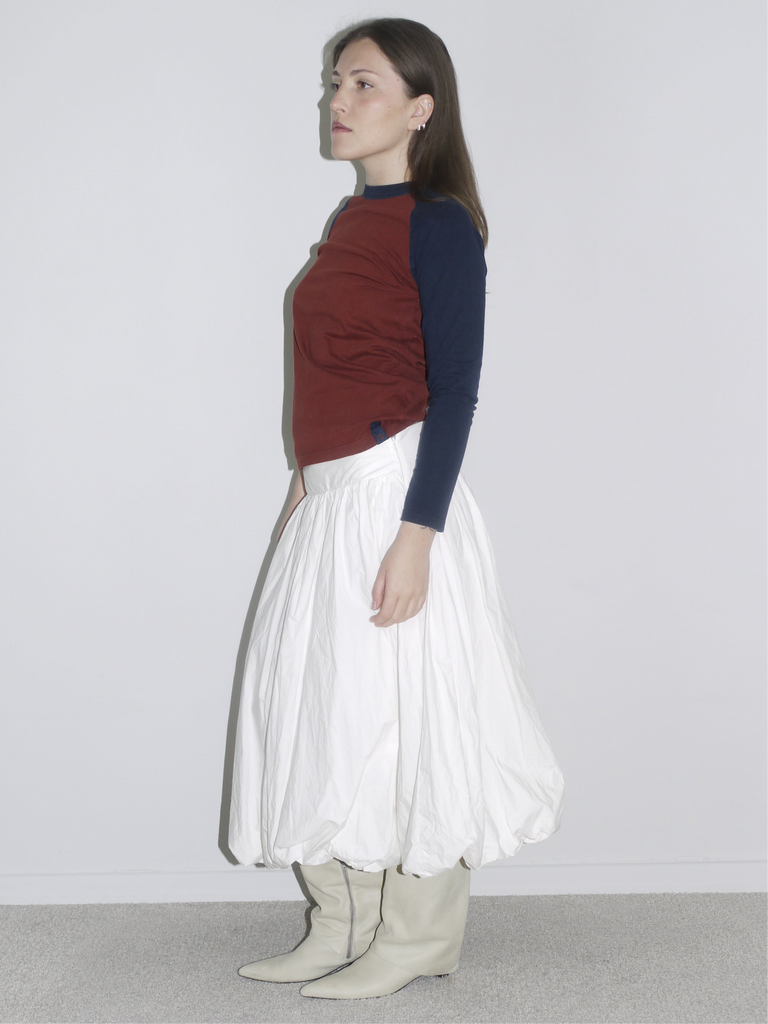 Fitted long-sleeve top with red body and navy sleeves tucked into a dramatic white skirt, giving Gimaguas meets Comme des Garçons vibes.