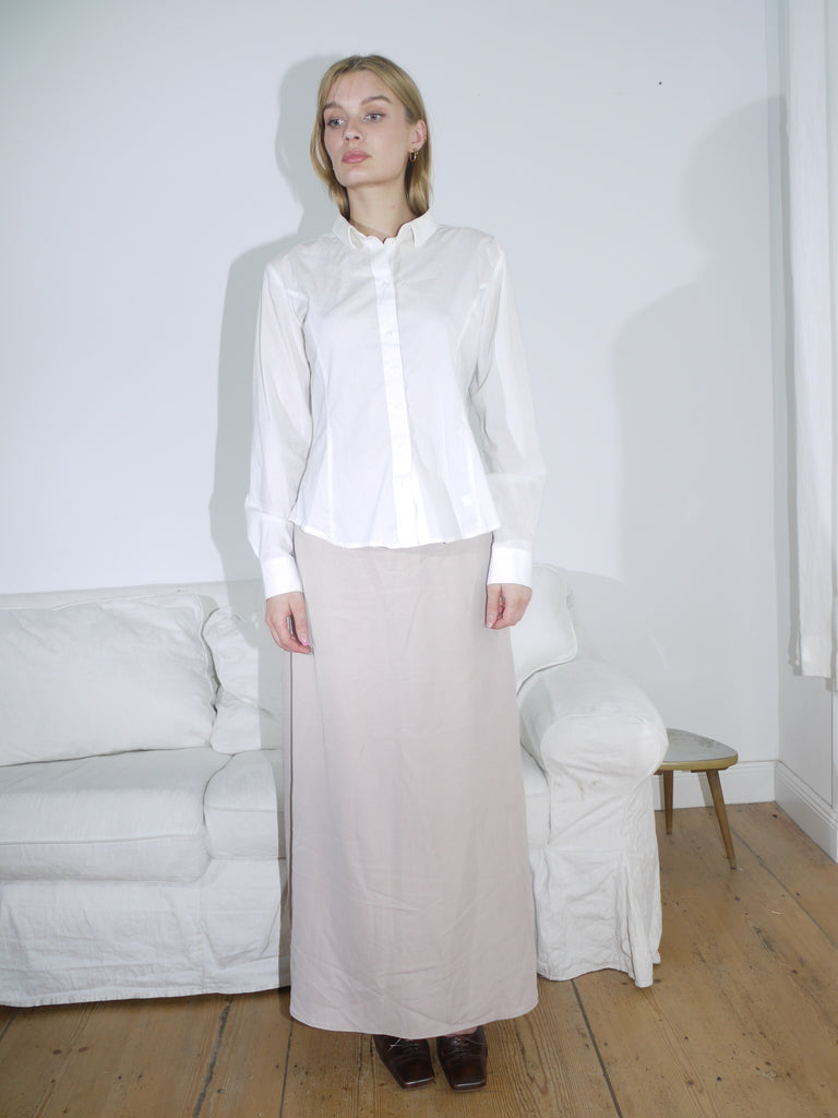 Model wearing a white G-Star button-up shirt with a structured fit and classic collar, paired with a beige skirt. Clean lines and subtle branding give it a sharp, minimal look.