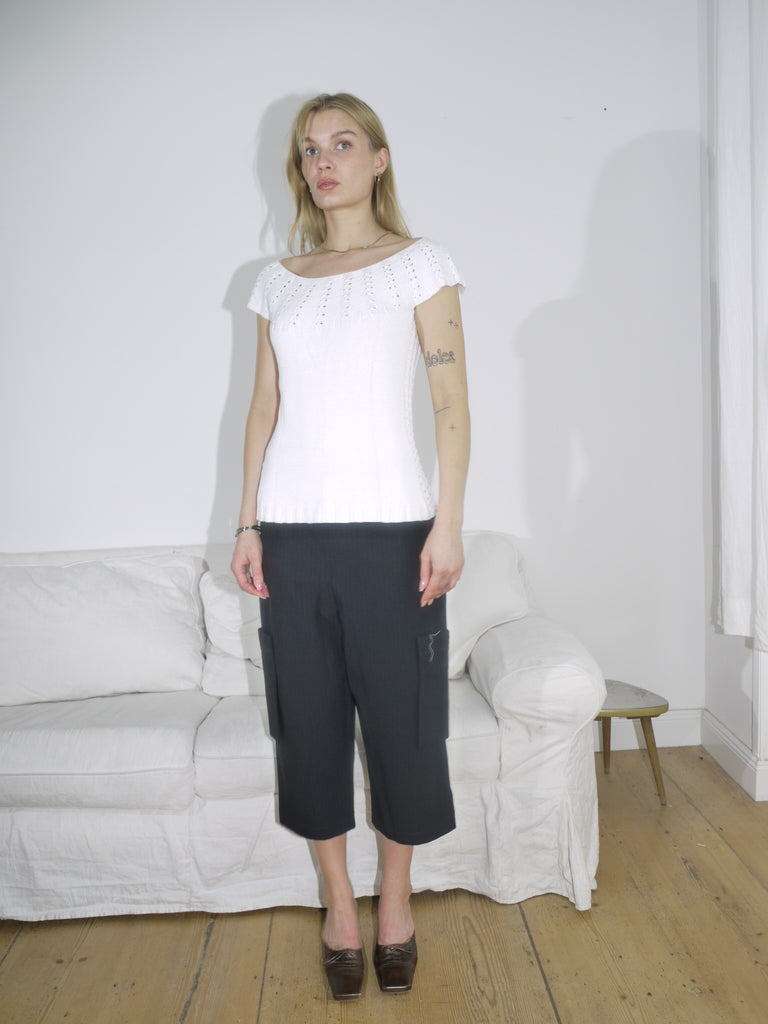 Model in a white eyelet knit top paired with structured black culottes. A clean monochrome look with playful texture and relaxed tailoring.