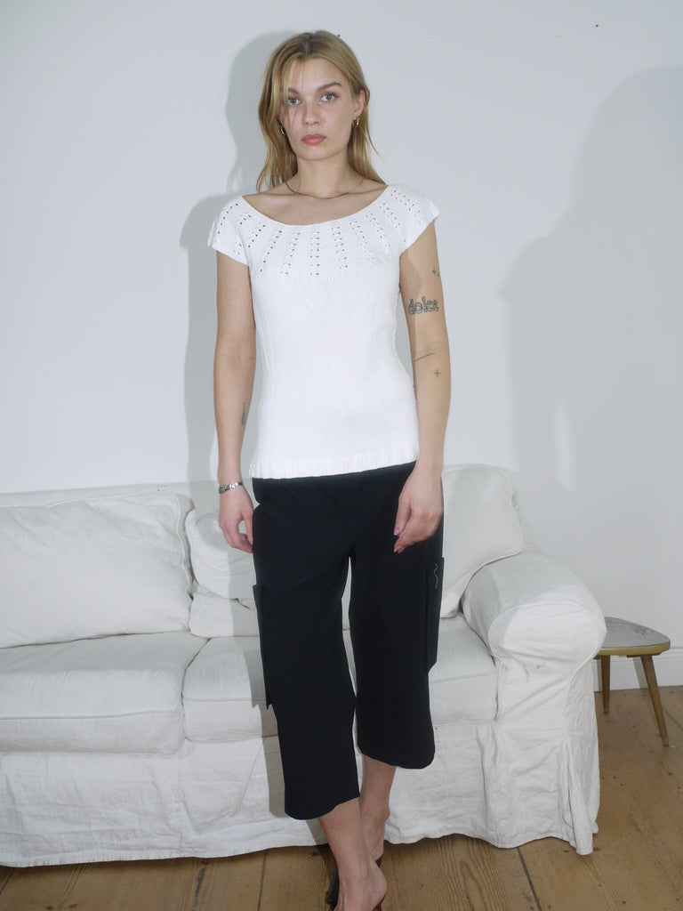 Model in a white eyelet knit top paired with structured black culottes. A clean monochrome look with playful texture and relaxed tailoring.