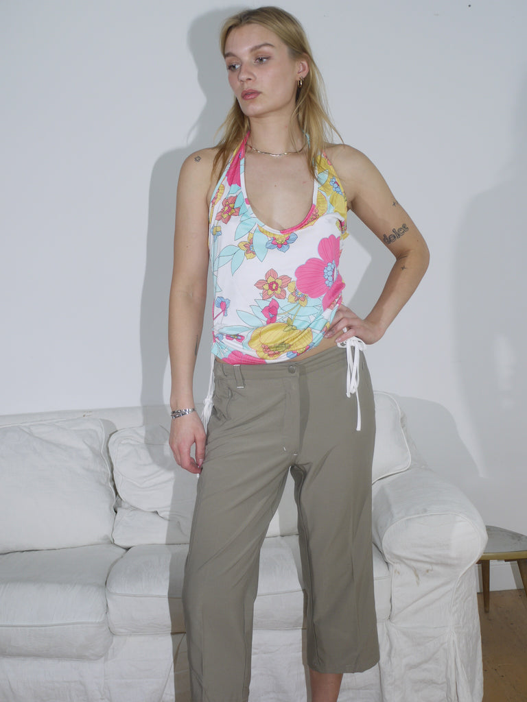 Model in a bold floral halter top with side drawstrings, styled with loose-fit khaki drawstring trousers. A playful Y2K-inspired look with tropical energy.